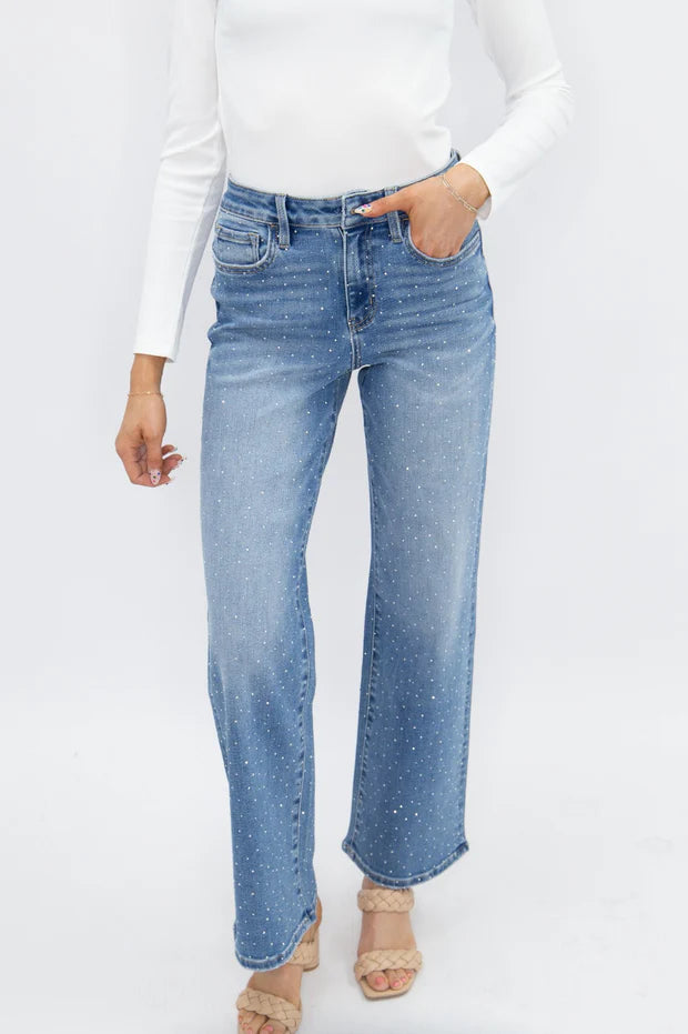 Woman wearing high rise rhinestone straight leg jeans with sparkling embellished denim and a relaxed fit.