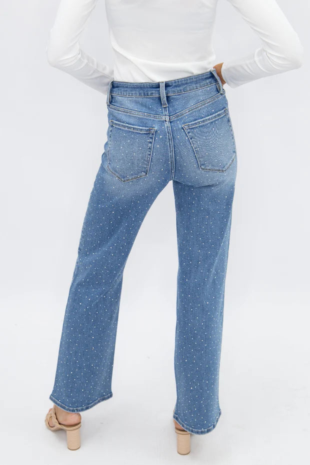 Woman wearing high rise rhinestone straight leg jeans with sparkling embellished denim and a relaxed fit.