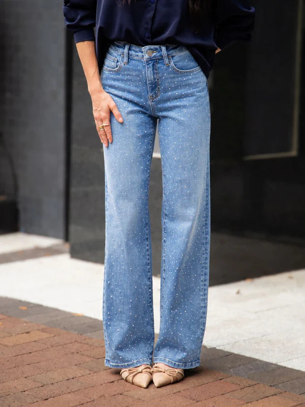 Woman wearing high rise rhinestone straight leg jeans with sparkling embellished denim and a relaxed fit.