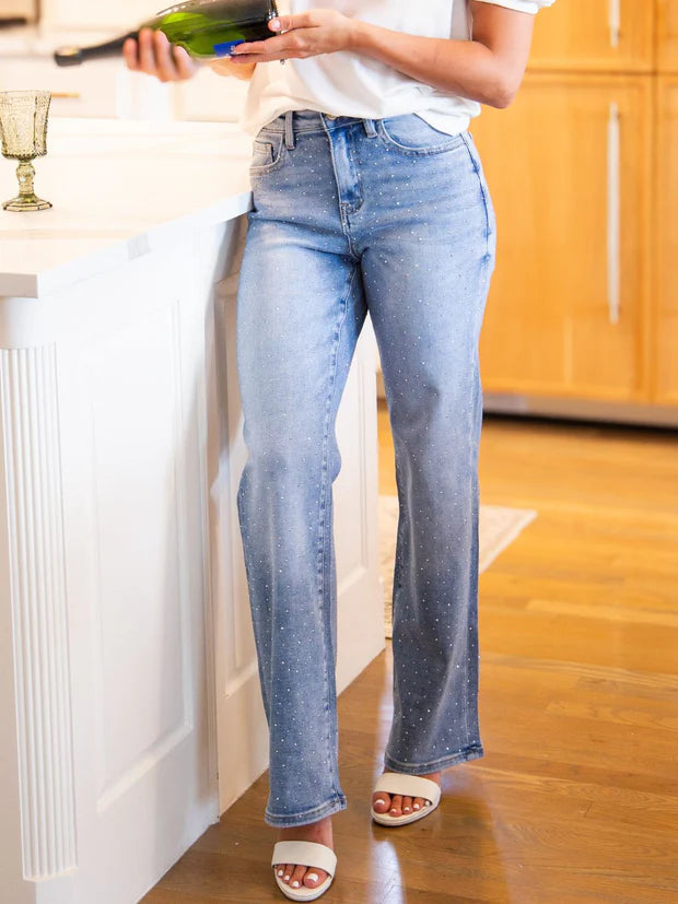 Woman wearing high rise rhinestone straight leg jeans with sparkling embellished denim and a relaxed fit.