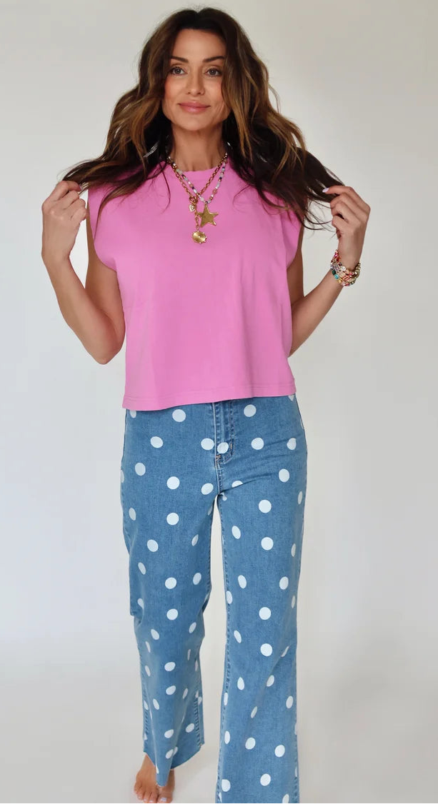 Woman wearing a pink top and blue polka dot pants against a plain background