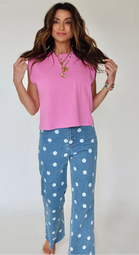 Woman wearing a pink top and blue polka dot pants against a plain background