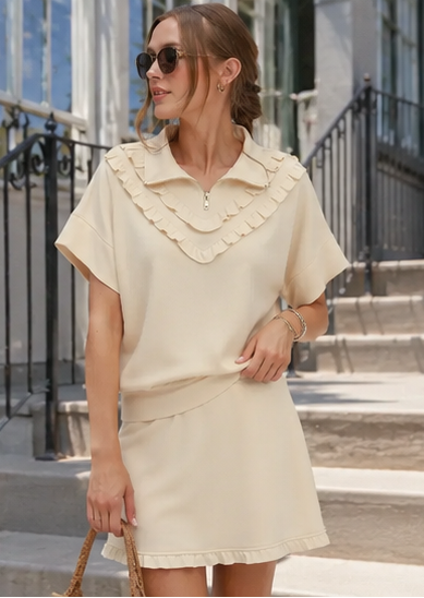 Woman wearing a beige dress with ruffled collar in an urban setting