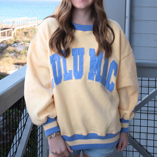 woman wearing oversized butter yellow sweatshirt with lavender graphic lettering