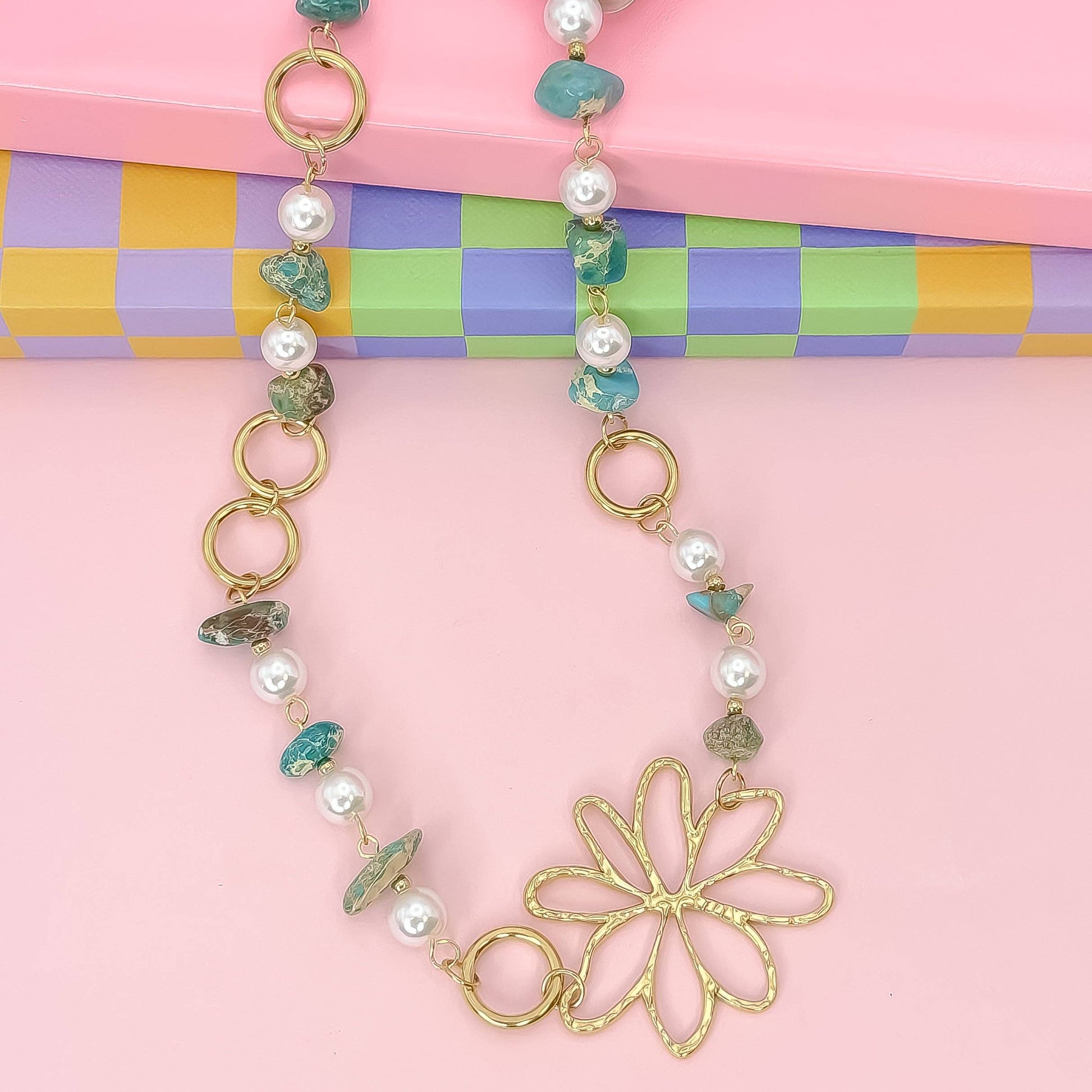 Necklace with floral clasp on a colorful checkered background