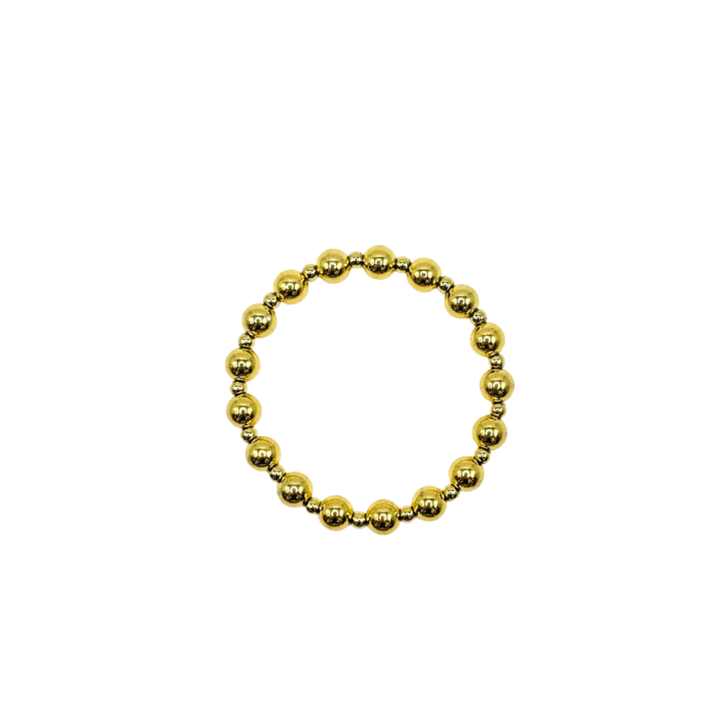 A gold beaded stretch bracelet made of polished metallic round beads, shown on a plain white background.