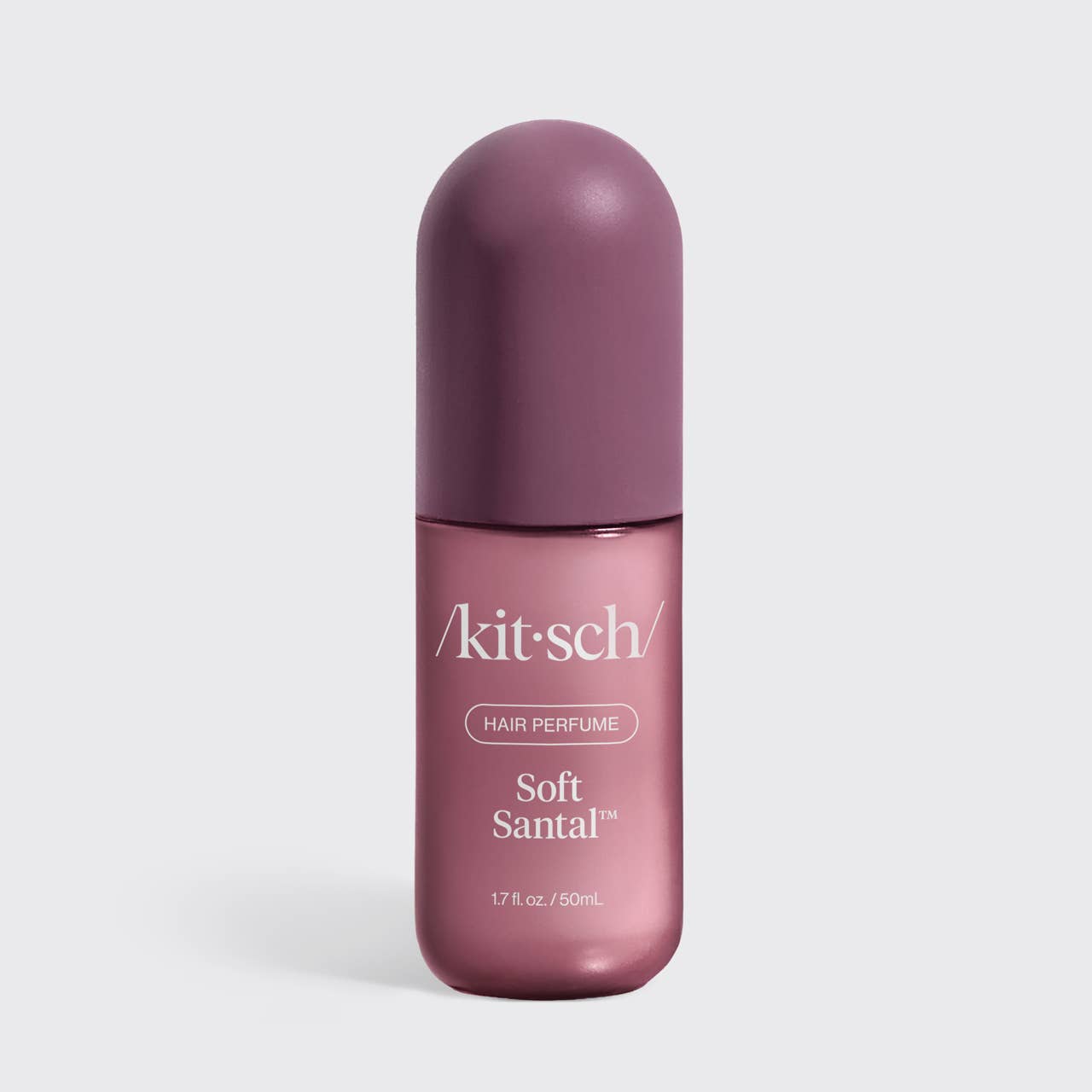 A bottle of kit-sch Soft Santal hair perfume, featuring a dusty purple cap and a metallic mauve-pink bottle with white text, set against a light gray background.