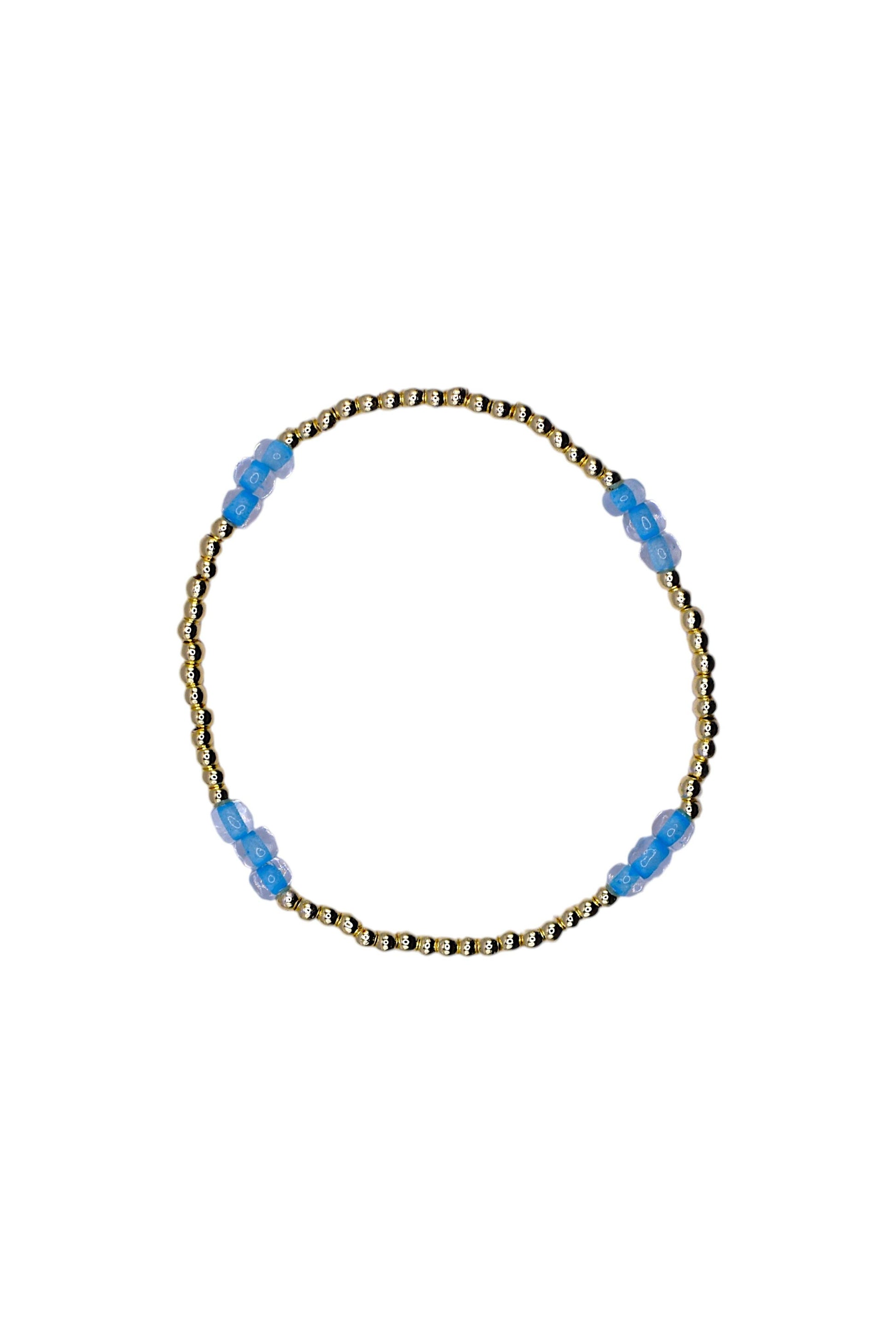 A delicate beaded bracelet with a gold-toned twisted wire base and small translucent light blue beads spaced along the top, shown on a plain white background.