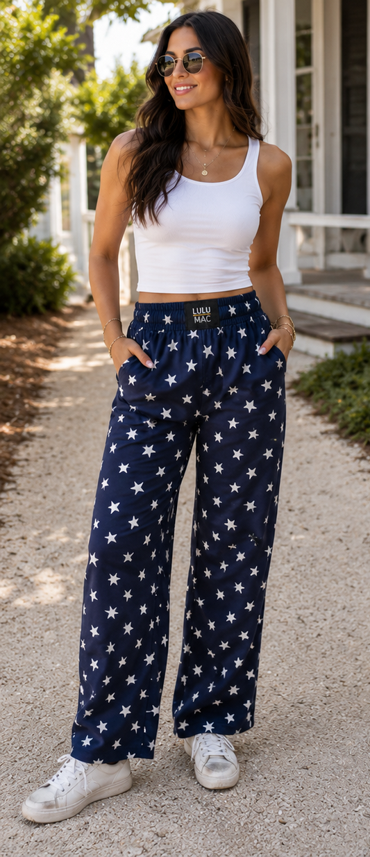 Woman wearing navy pants with white star pattern and white tank top, sitting on steps.
