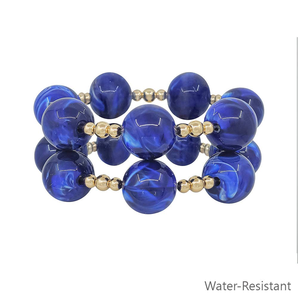 Blue beaded bracelet with gold accents on a white background
