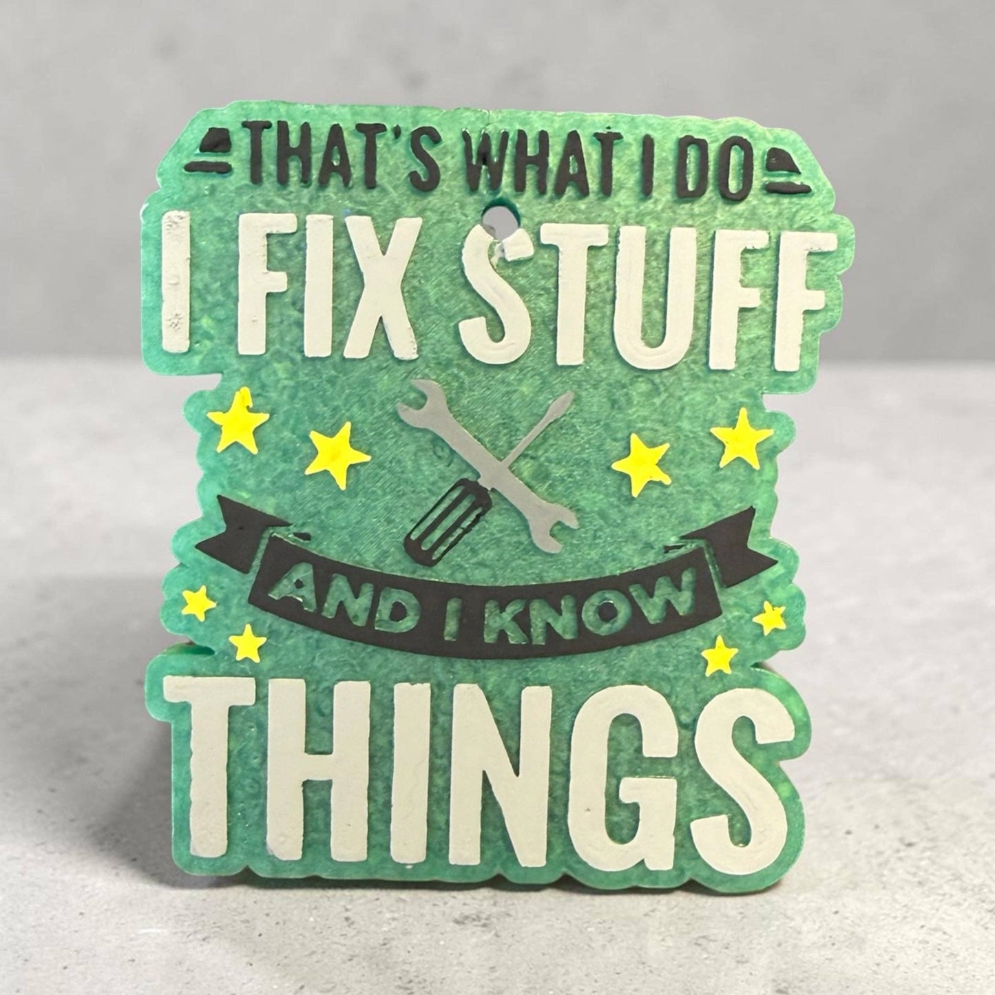 Decorative sign with text 'That's what I do, fix stuff and I know things' on a gray background