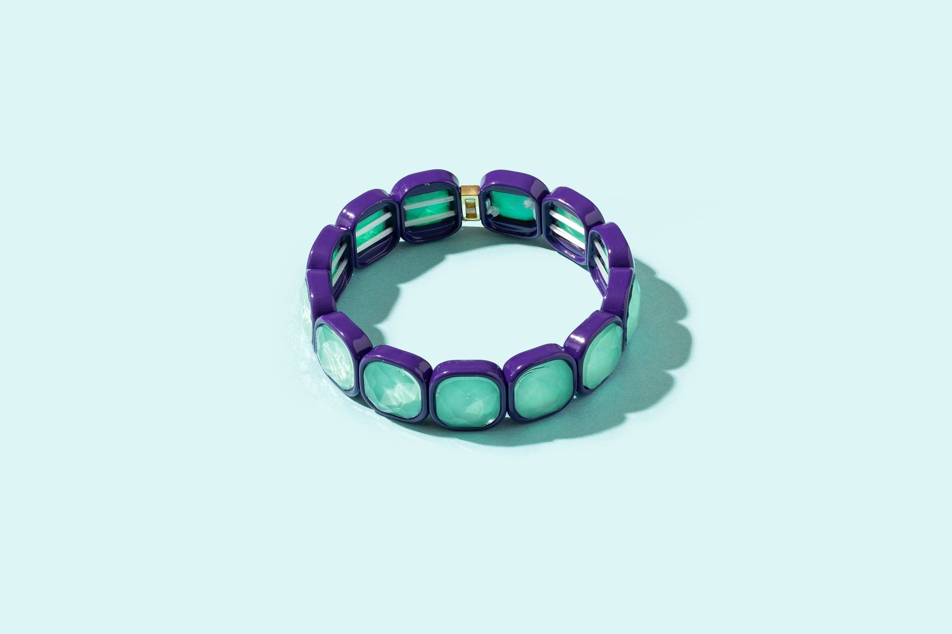 Purple and green bracelet on a light blue background