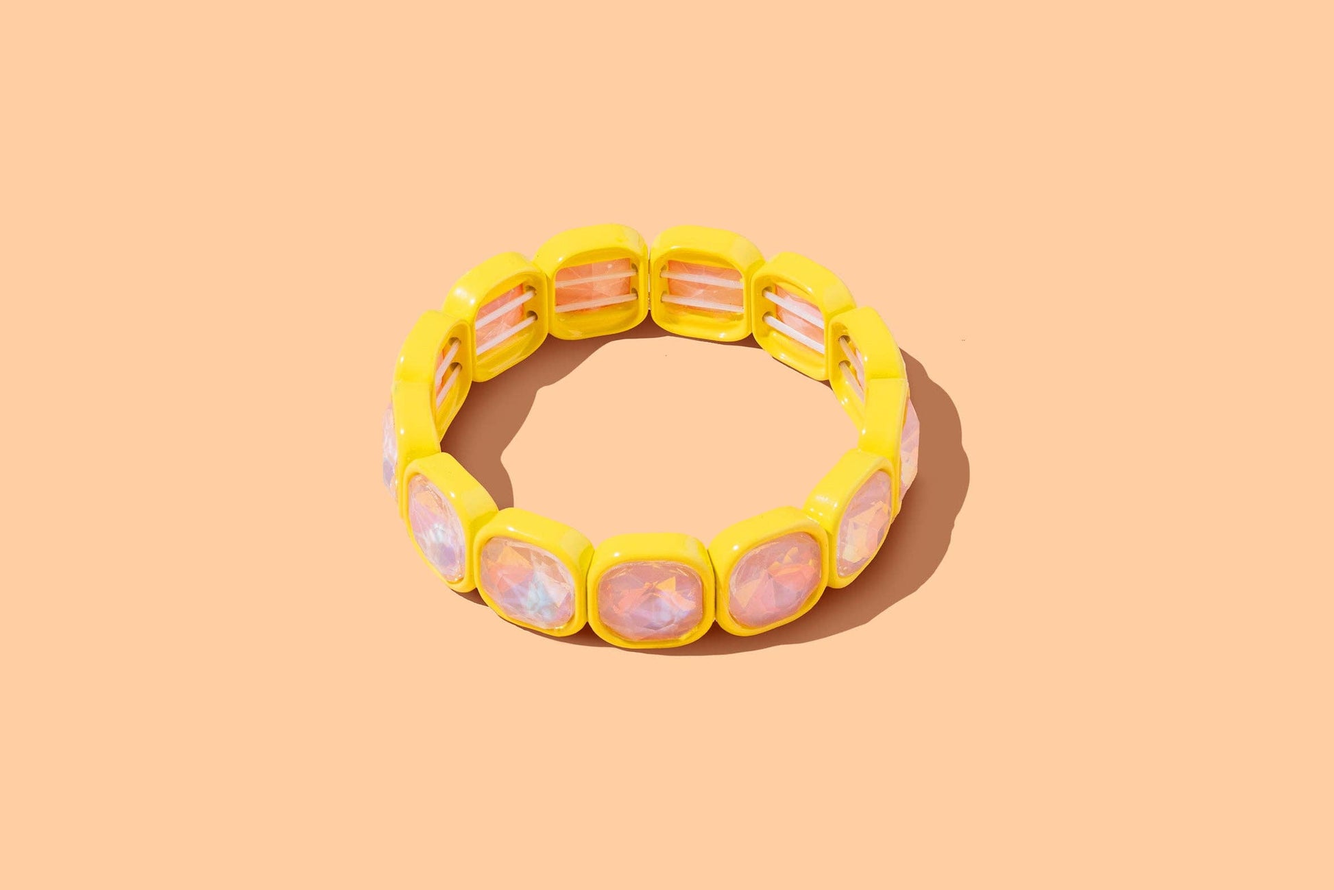 Yellow bracelet with pink stones on a peach background