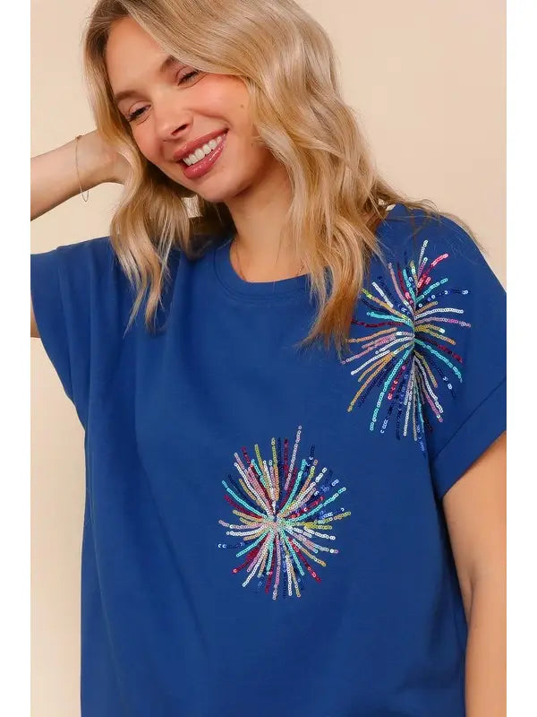 Woman wearing a blue t-shirt with colorful firework designs on a beige background