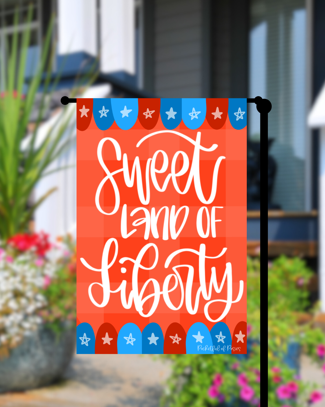 Decorative flag with 'Sweet Land of Liberty' text in a garden setting