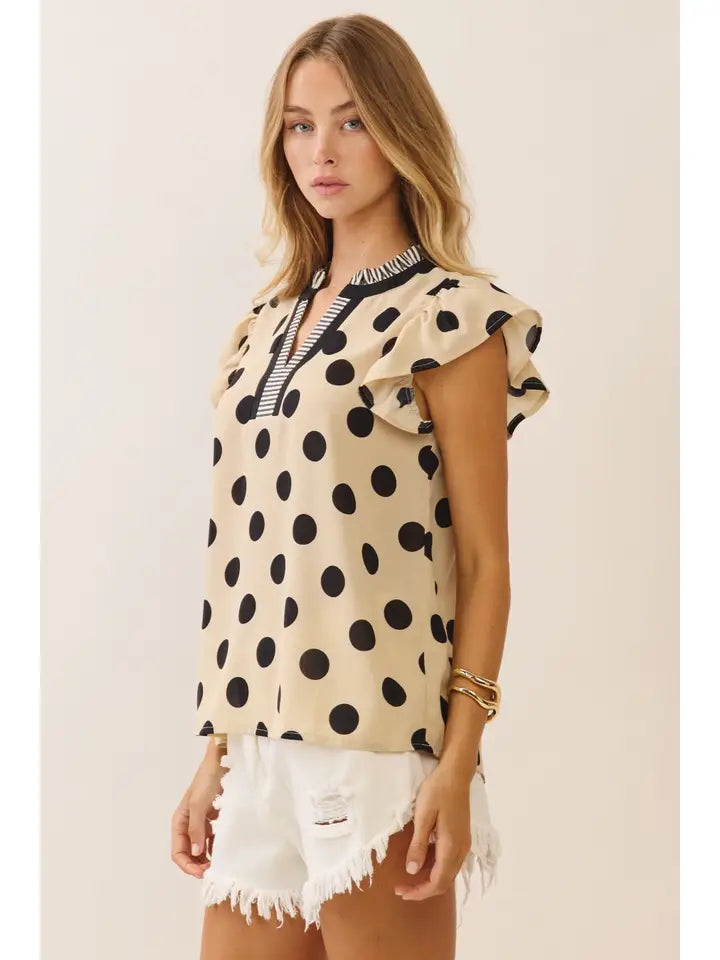 Woman wearing a polka dot top and white shorts against a plain background