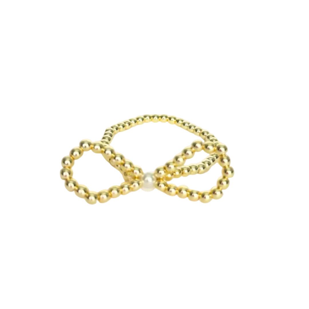 Gold bow-shaped jewelry with a pearl center on a white background