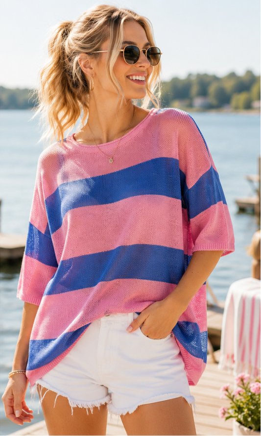 Two women wearing colorful tops and white shorts by a waterfront.