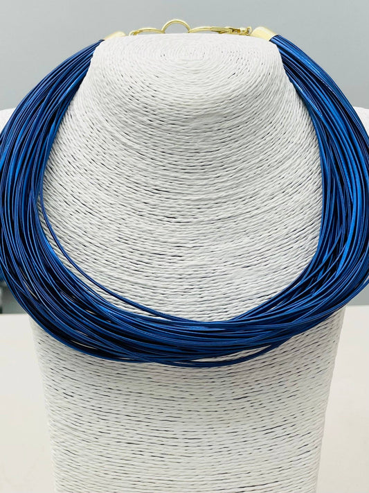 Blue necklace on a white mannequin bust against a gray background
