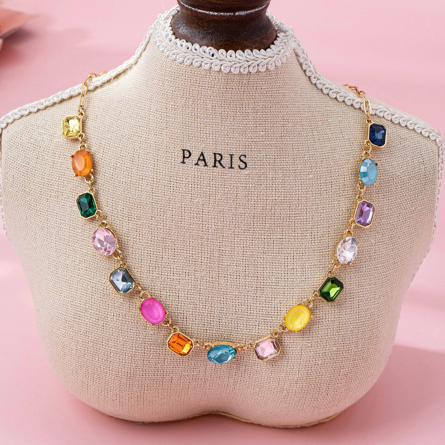 Necklace with colorful beads on a 'PARIS' branded mannequin bust against a pink background