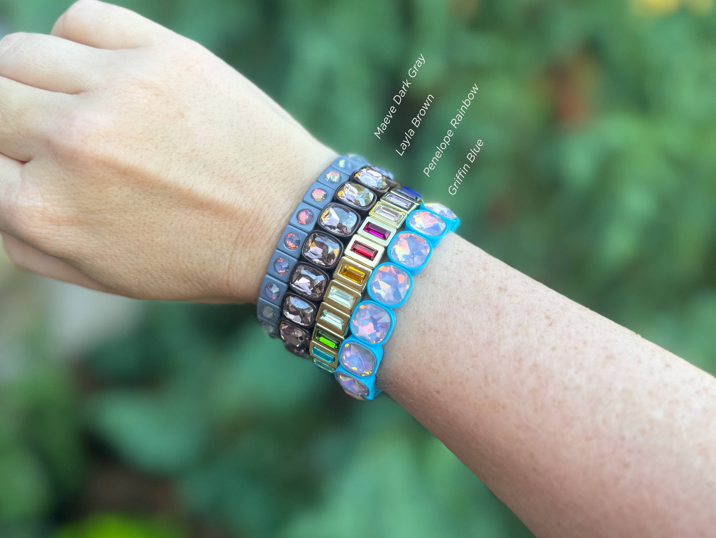 Multicolored beaded bracelets on a wrist with a blurred green background