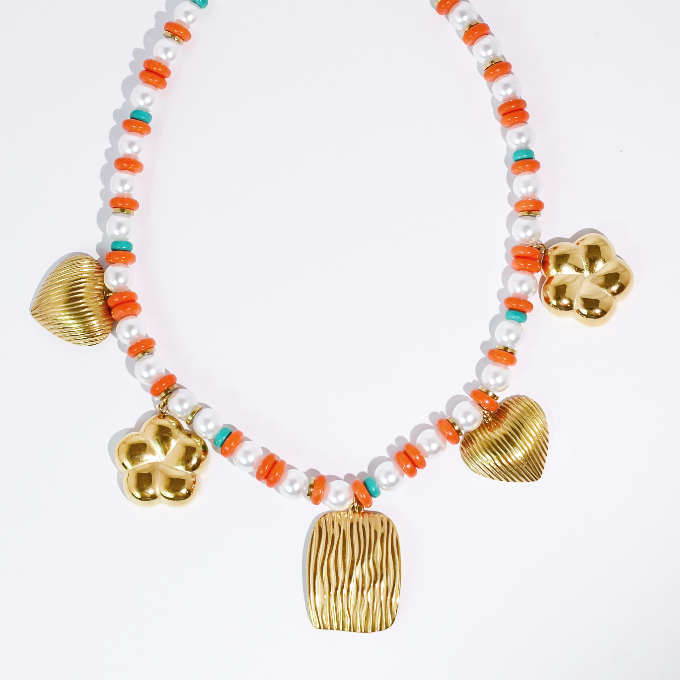 Necklace with gold charms and white beads on a light gray background