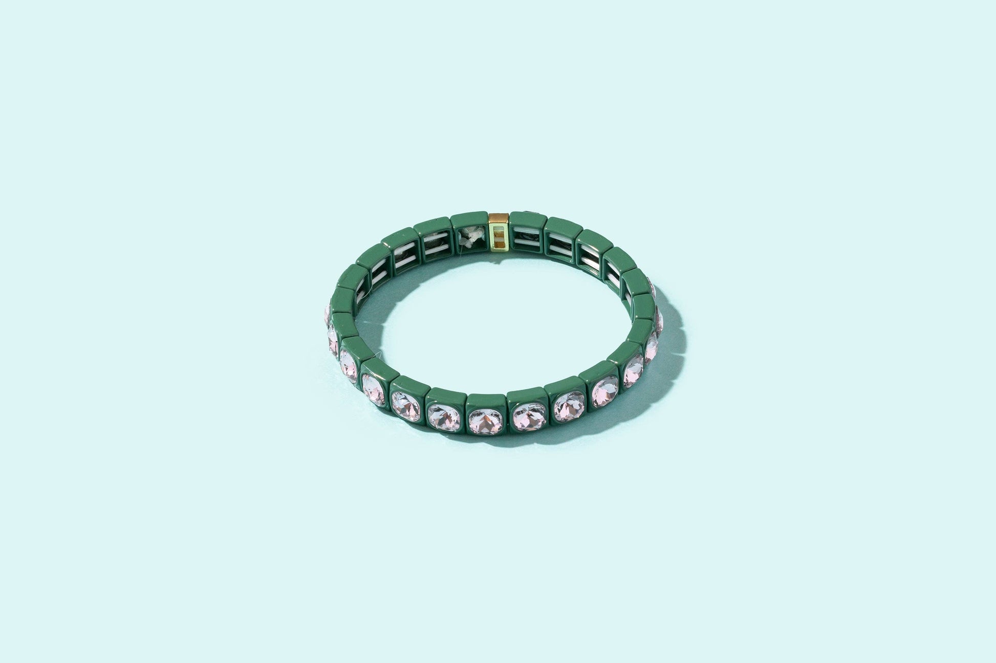 Green bracelet with gemstones on a light blue background