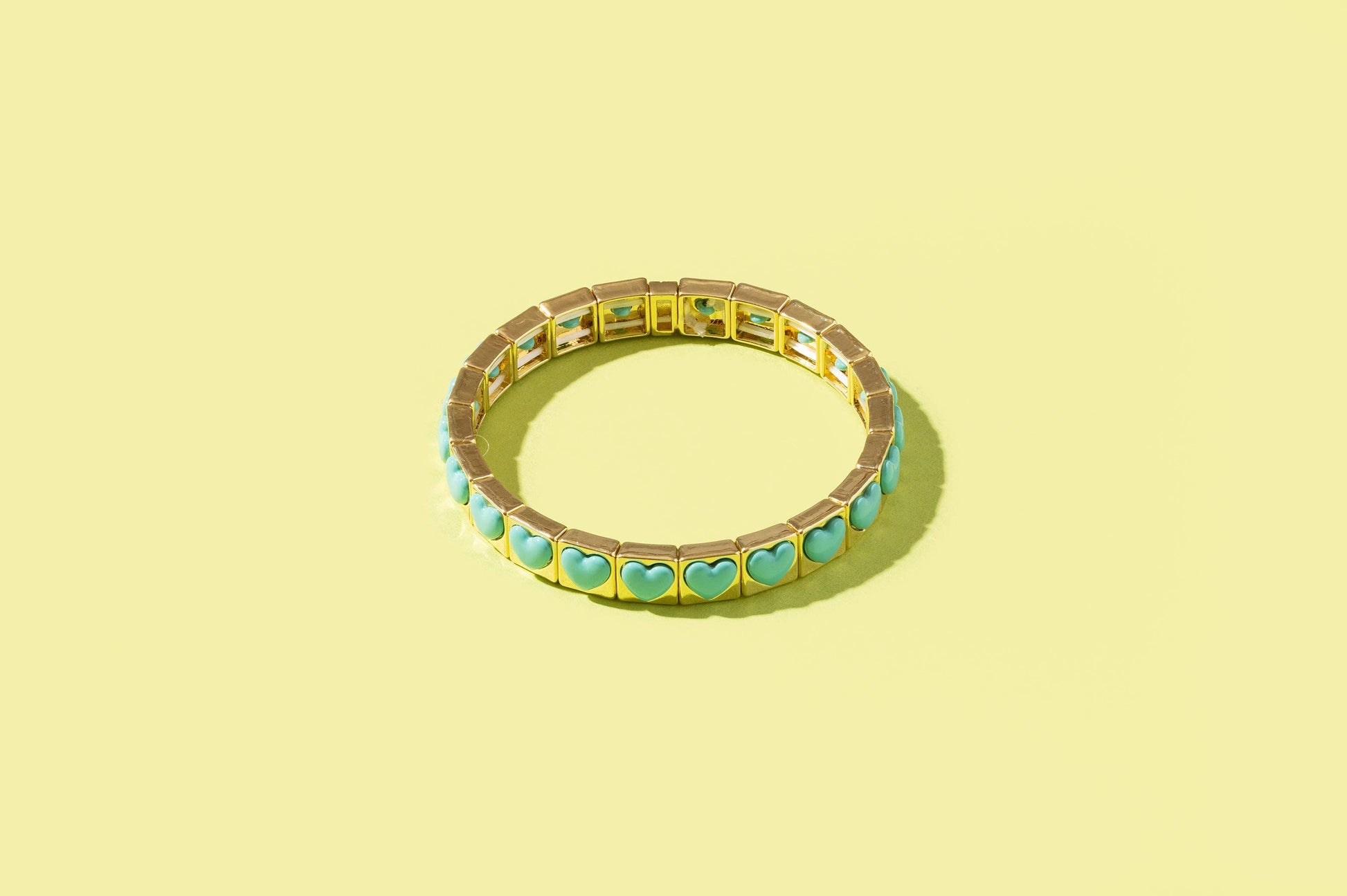 Gold bracelet with turquoise stones on a yellow background