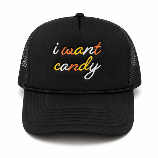 A black trucker hat with 'i want candy' embroidered on the front in white, orange, and yellow script, shown against a plain white background.