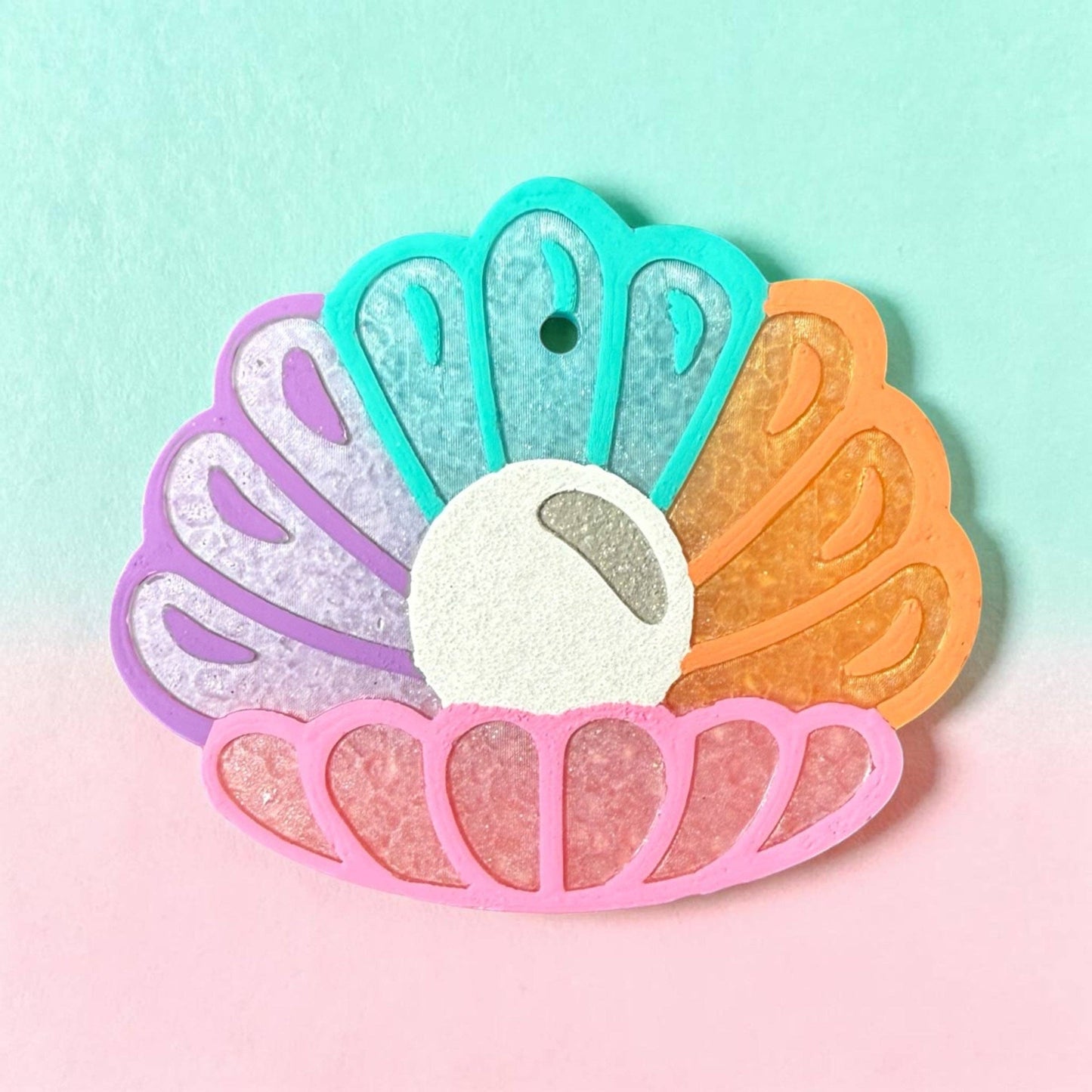 Colorful shell-shaped object with gradient colors on a pastel background