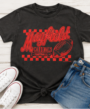 A black graphic t-shirt featuring a red 'Mayfield Cardinals Football' design with a football illustration and checkered border, styled in a flat lay with blue jeans and white sneakers on a white wood background.