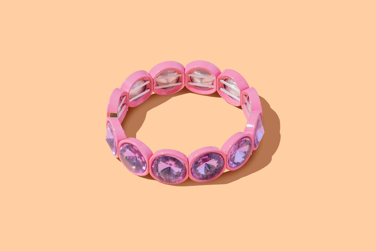 Pink bracelet with purple gemstones on a peach background