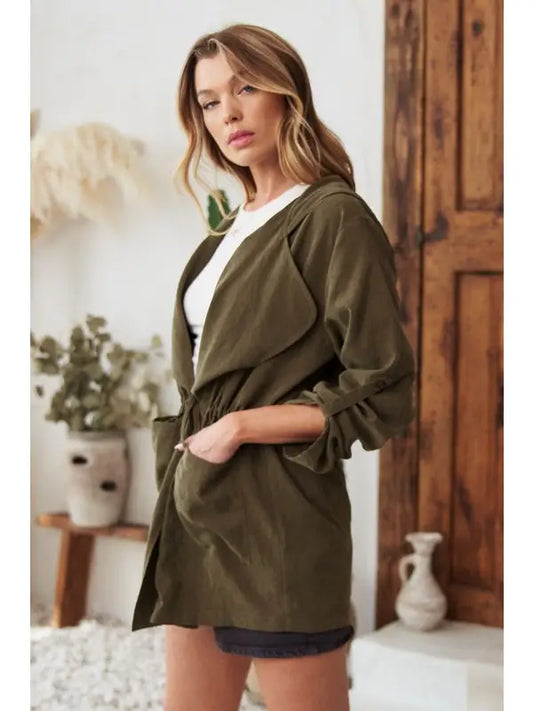 Olive lightweight hooded jacket, side view with hand in pocket, worn over black shorts and white top
