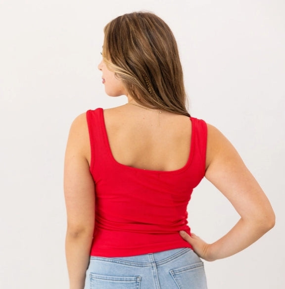 Woman wearing a red tank top and blue jeans on a white background