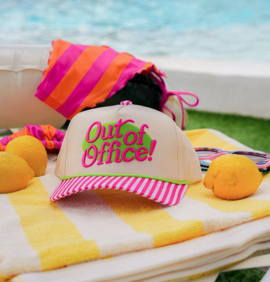 Colorful cap with 'Out of Office!' text on a towel by the beach